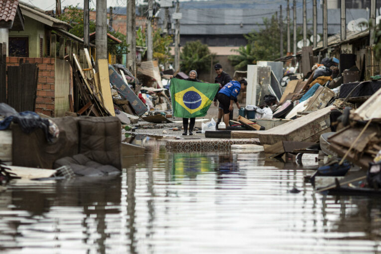 Una mujer sostiene una bandera de Brasil en medio de una calle afectada por las inundaciones, este lunes 3 de junio en Porto Alegre, Rio Grande do Sul (Brasil).