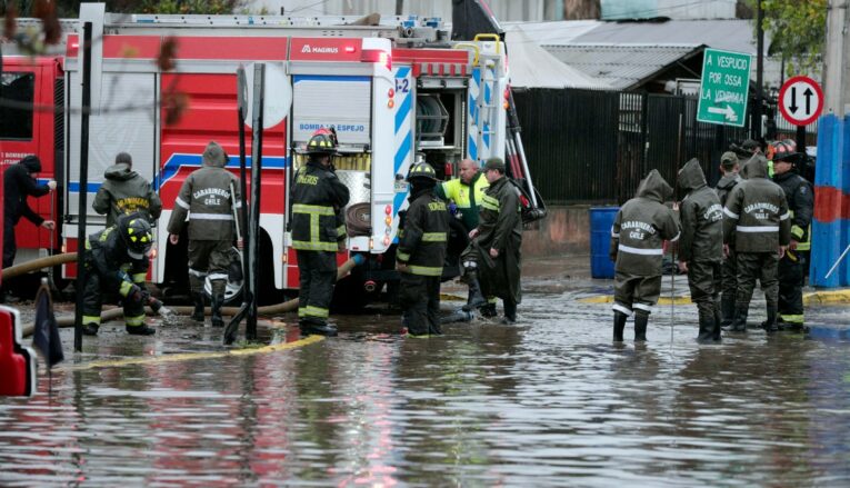 Carabineros y bomberos trabajan en calles inundadas por la lluvia en Santiago, el 13 de junio de 2024.