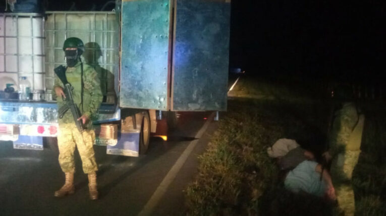 Un guardia nacional junto a ciudadanos detenidos por la perforación del Poliducto Santo Domingo-Macul-Pascuales, en Guayas.