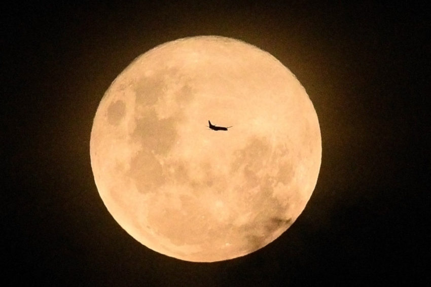 La silueta de un avión se perfila sobre la superficie de la luna llena, en Sídney, Australia.