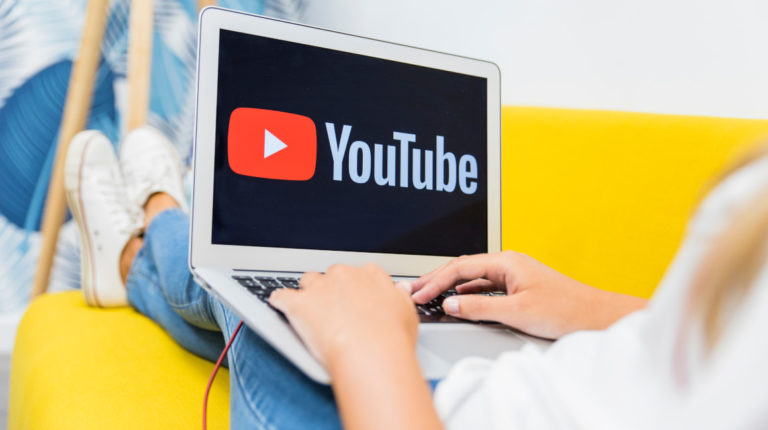 Mujer trabajando en un computador con el logo de YouTube en la pantalla
