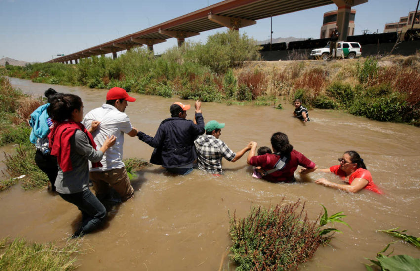Migrantes hondureños y salvadoreños hacen una cadena para cruzar el Río Bravo en la frontera entre México y Estados Unidos.