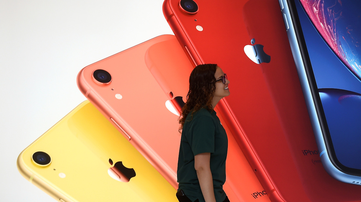 Una empleada de Apple camina frente a una ilustración de iPhone en el local de la empresa en la librería Carnegie en Washington, Estados Unidos.