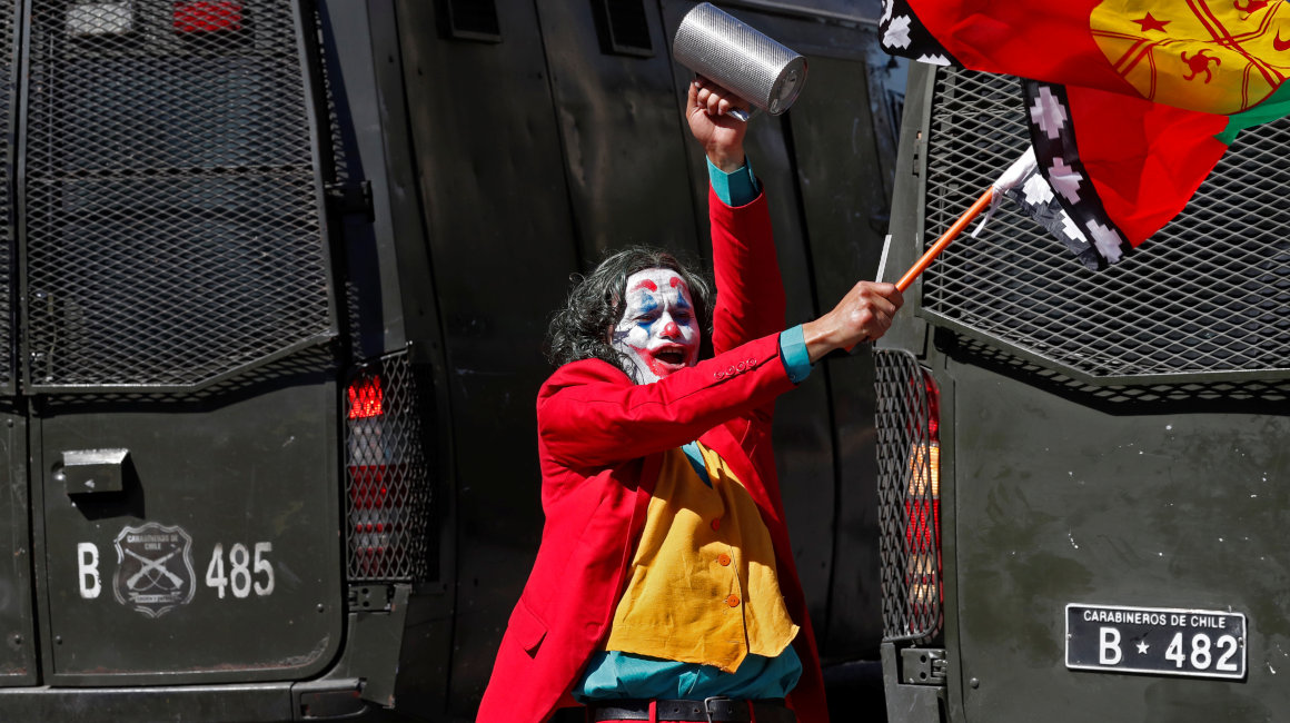 Un manifestante vestido como el personaje de ficción Joker usa una bandera Mapuche durante las protestas en Chile.
