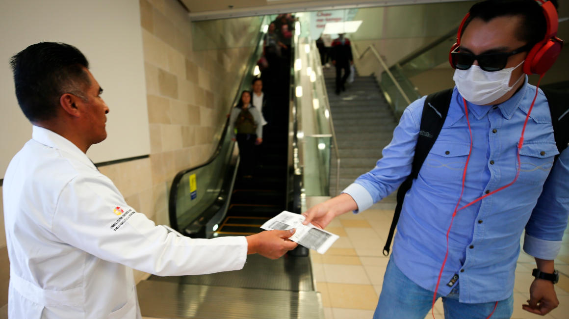 Un representante del Ministerio de Salud Pública de Ecuador entrega folletos informativos a pasajeros que provienen de distintos países, en medio de tareas preventivas dada la situación del coronavirus, en el Aeropuerto Internacional Mariscal Sucre, en Quito.