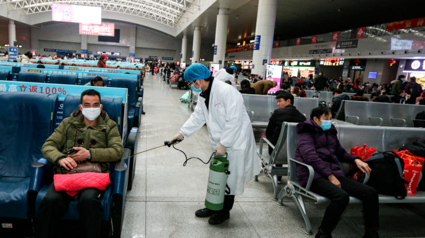 Un operario desinfecta una zona de espera para pasajeros en la estación de tren en China