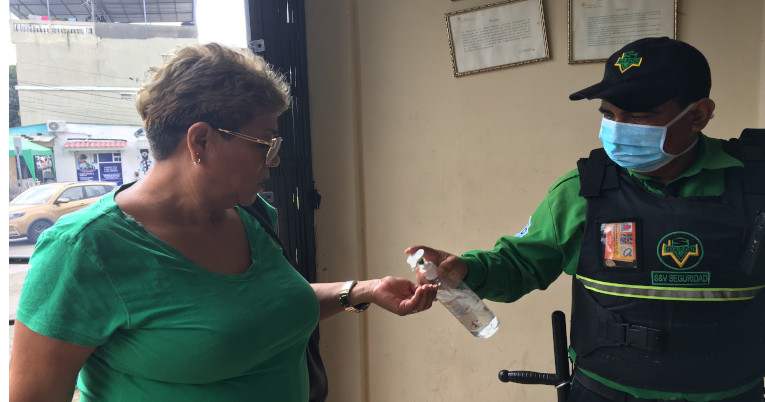 Un guardia de seguridad entrega gel antibacterial a cada paciente que ingresa al centro de salud primario en Guayaquil. 