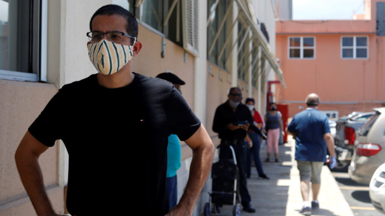 Un hombre usa una mascarilla de protección ante el Covid-19, mientras espera en la fila en San Juan, Puerto Rico.