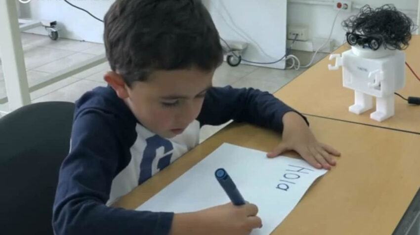 Niño escribiendo junto a Nacho.