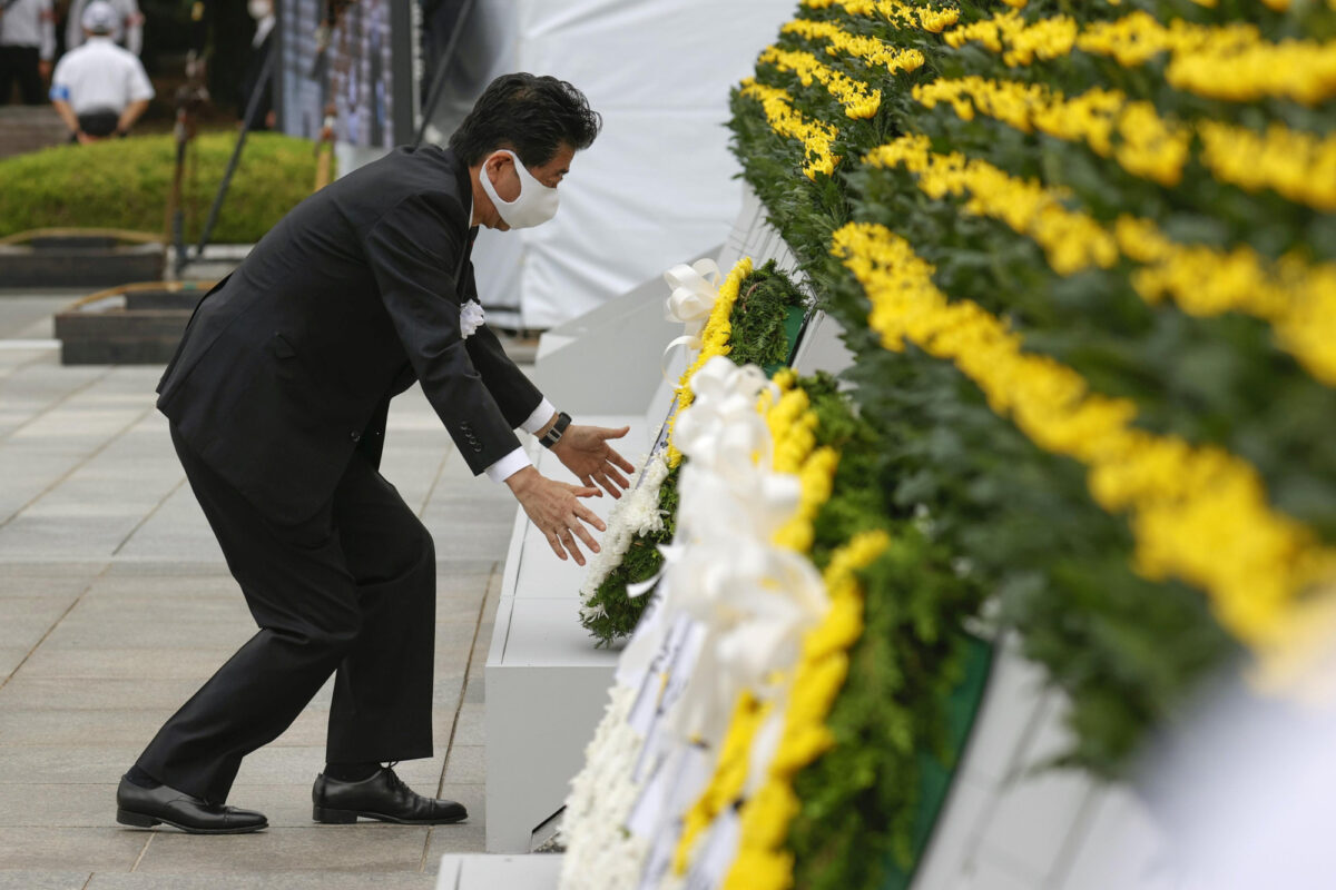 El primer ministro de Japón, Shinzo Abe, con una máscara protectora, ofrece una corona de flores para las víctimas del bombardeo atómico de 1945, en el Parque Memorial de la Paz en Hiroshima, Japón, el 6 de agosto de 2020, en el 75 aniversario del bombardeo atómico de la ciudad.