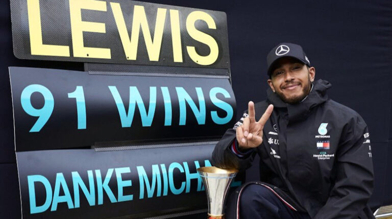Lewis Hamilton posa junto al cartel que retifica sus 91 victorias en la Fórmula 1, las mismas que Schumacher