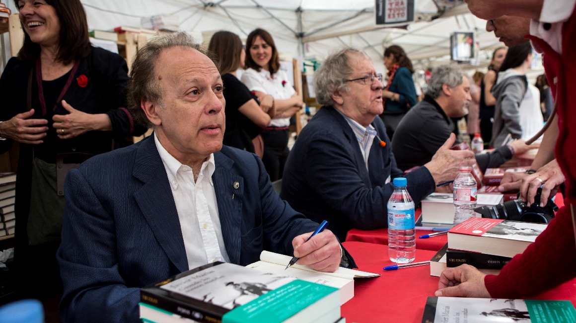 El escritor Javier Marias (i) firma ejemplares de su libro a sus lectores junto a Ian Gibson (c) y Manuel Rivas (d) durante la diada de Sant Jordi, la tradicional fiesta del libro y de la rosa, en abril de 2018.