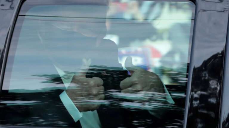 El presidente Donald Trump gesticula desde el carro frente al Walter Reed National Military Medical Center