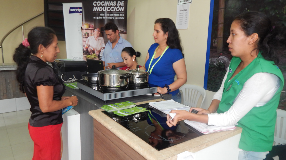 Funcionarios de CNEL en Santo Domingo ofertan las cocinas de inducción, en 2019.