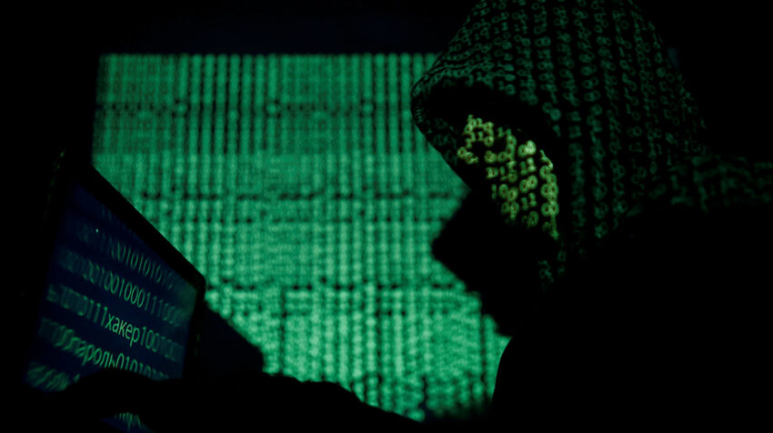 Ilustración. Hombre encapuchado sostiene una computadora portátil mientras el código cibernético se proyecta sobre él.