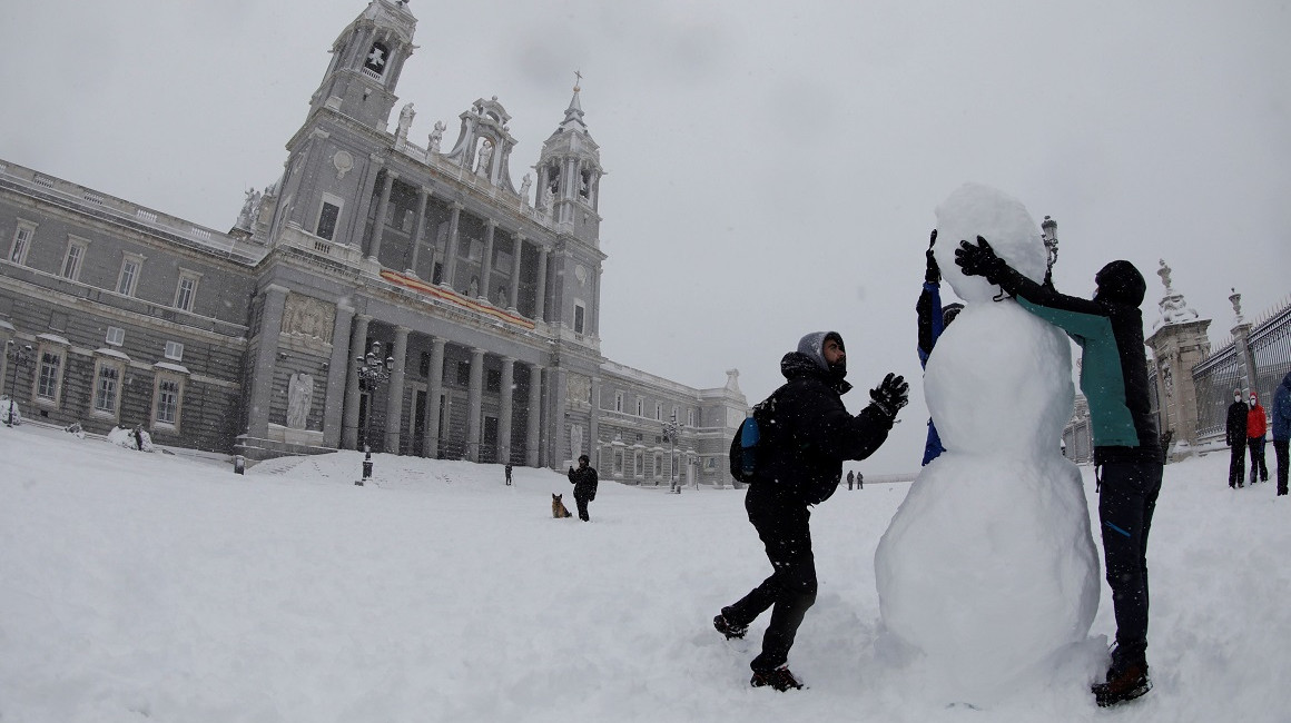 Personas hacen un muñeco de nieve en las inmediaciones de la Catedral de la Almudena, en Madrid, el 9 de enero de 2021.