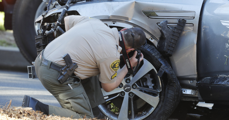 Un agente de la policía saca fotos a una de las partes afectadas del auto de Woods.
