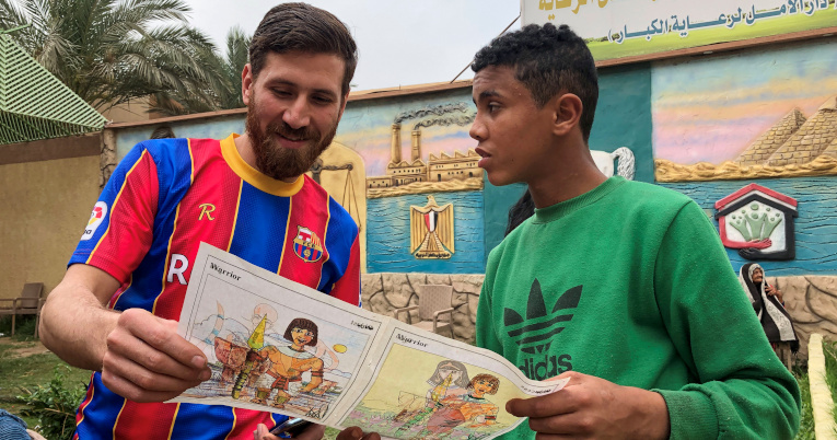 Islam Battah, el egipcio parecido a Lionel Messi, mira una revista con un niño egipcio, el 23 de marzo de 2021.