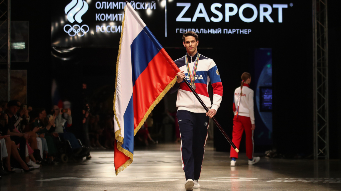 Una modelo camina por la pasarela con la bandera rusa durante la presentación de los uniformes oficiales que usarán los deportistas rusos y que fueron diseñados por Zasport para los Juegos Olímpicos de Tokio.