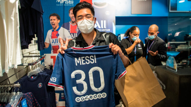 Un aficionado posa con la camiseta de Messi dentro de la tienda del PSG.