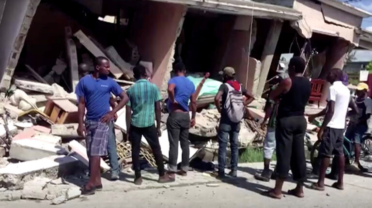 Personas en los alrededores de una construcción colapsada en Los Cayos, Haití, después de un terremoto este 14 de agosto de 2021.