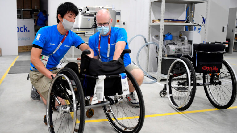 Técnicos reparan una silla de ruedas en el taller de la Villa Paralímpica de Tokio.