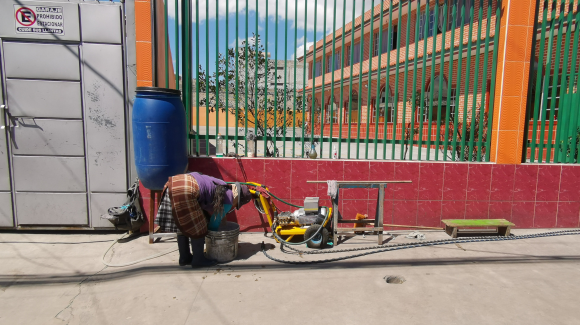 Una mujer instala una lavadora de autos improvisada sobre la calle Cusubamba, en el sur de Quito, el 3 de septiembre de 2021.