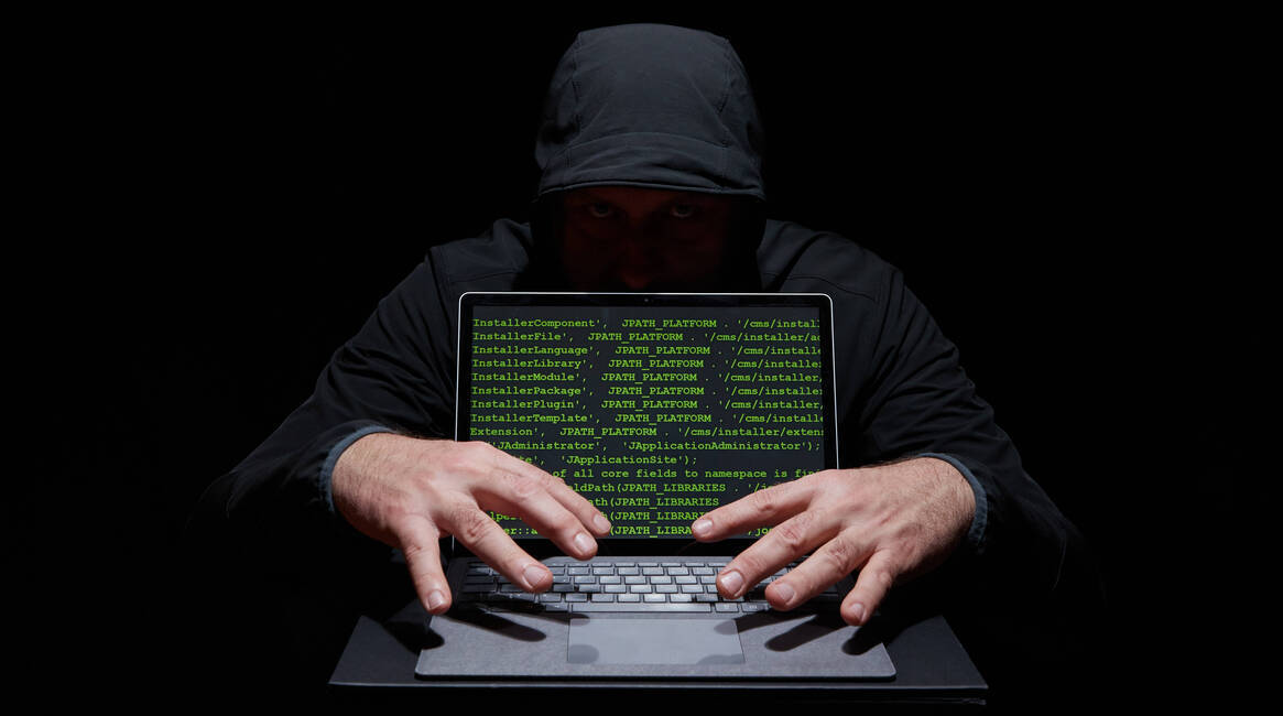 Ilustración. Un hombre atrás de una computadora que muestra un código.