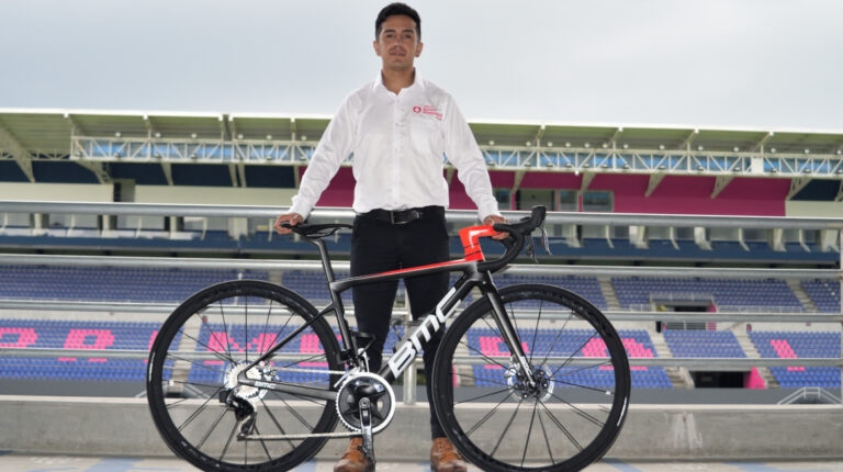 Diego Puetate posa con la bicicleta BMC que usarán los ciclistas del Team Banco Guayaquil durante la temporada 2022.