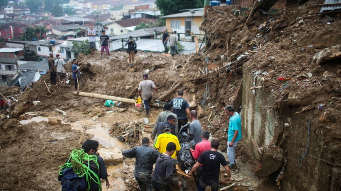 Hombres transportan un cuerpo en un deslizamiento de lodo en Morro da Oficina, tras las inundaciones en Petrópolis, Brasil, del 16 de febrero de 2022.