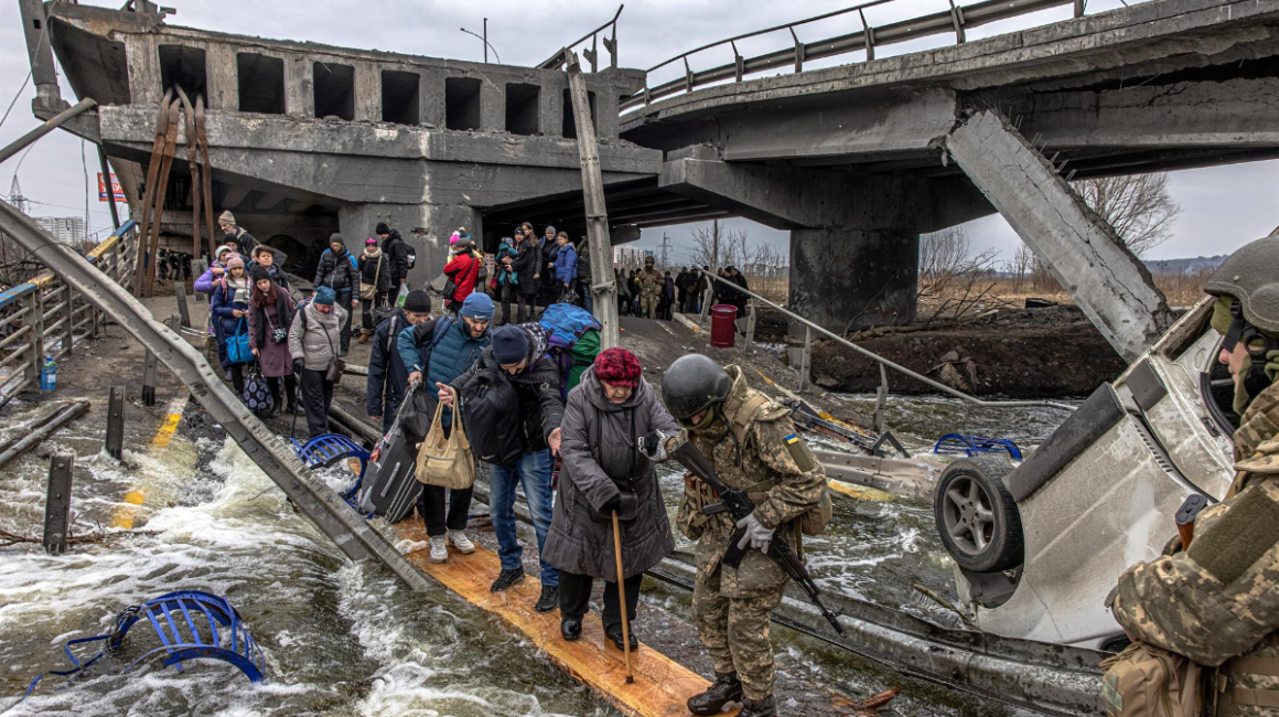 Civiles cruzan un puente destruido mientras huyen del asedio en la ciudad de Irpin, a unos 20 km de la capital, en Ucrania, el 7 de marzo de 2022.