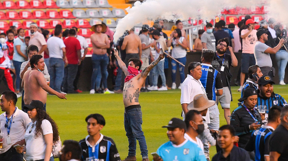 Aficionados en medio de la cancha del Estadio la Corregidora luego de los hechos violentos que se originaron en los graderíos, el 5 de marzo de 2022.