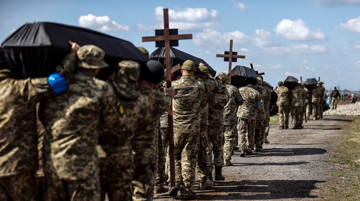 Soldados de Ucrania cargan a hombros los ataúdes con los restos de sus compañeros, en un funeral y entierro colectivo celebrado en el cementerio militar de Dnipro, el 6 de abril de 2022.
