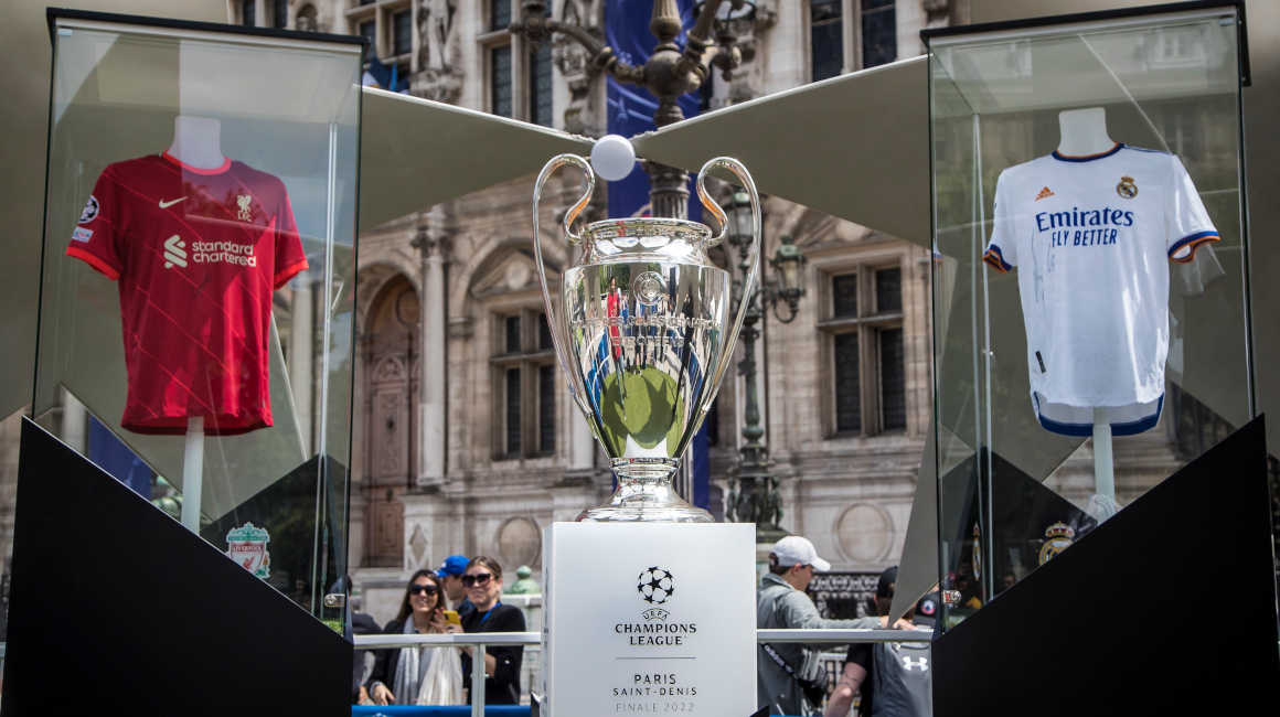 El trofeo de la Champions League se muestra entre las camisetas del Liverpool y el Madrid en el fan zone de París, el 26 de mayo de 2022.