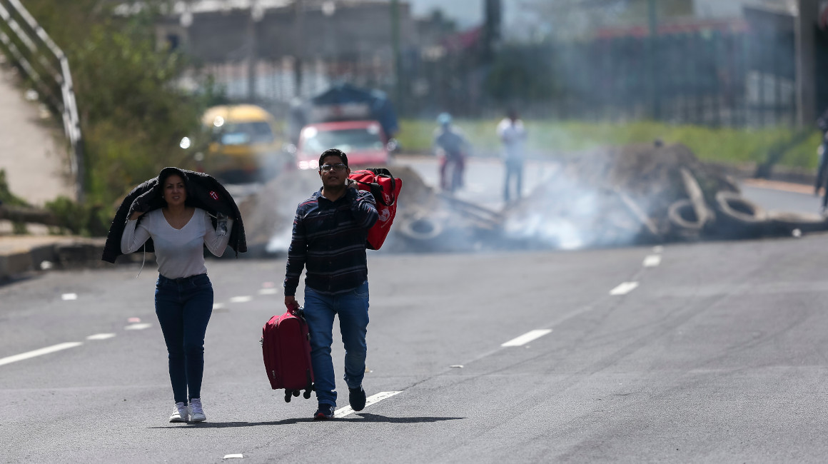 Dos personas caminan con maletas en una carretera que fue bloqueada al ingreso norte de Quito, el 13 de junio de 2022.