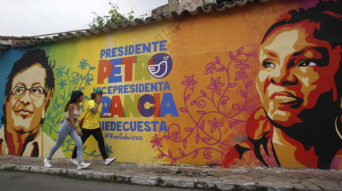 Transeúntes caminan frente a un mural pintado con publicidad electoral del candidato presidencial Gustavo Petro, en Piedecuesta, el 19 de junio de 2022. 