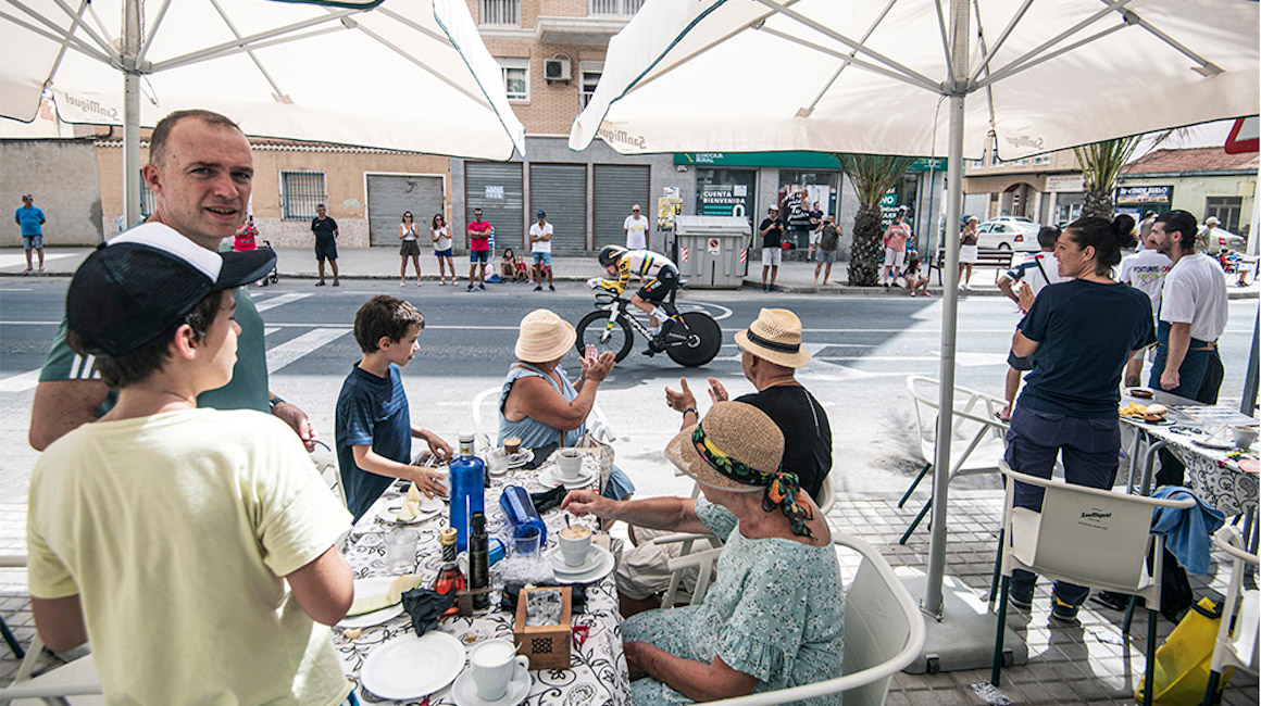 Aficionados disfrutan de la Etapa 10 de la Vuelta a España desde las mesas de un restaurante.