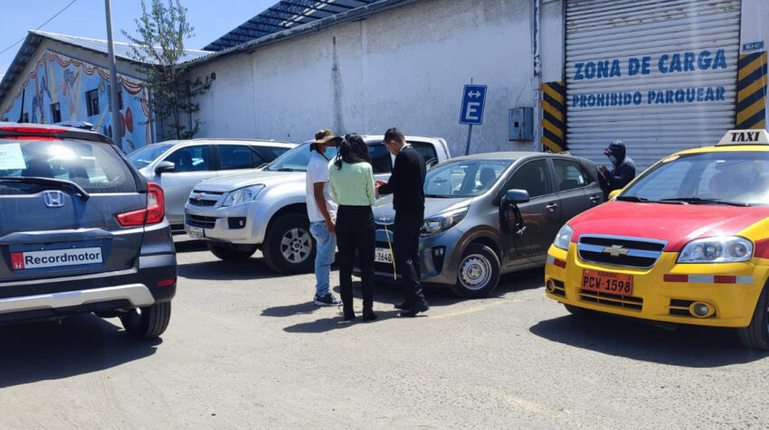 Vendedores de repuestos instalan la placa en un auto en el centro de revisión vehicular Bicentenario, en el norte de Quito, el 13 de septiembre de 2022.