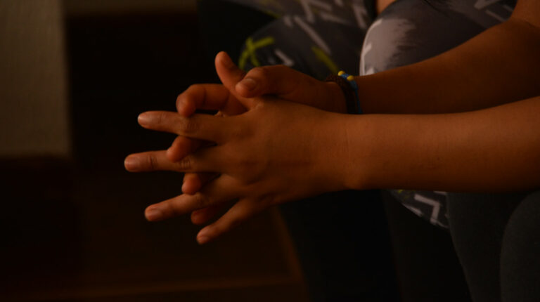 Una adolescente entrelaza sus dedos, en una casa de acogida en Ecuador. Imagen de archivo.