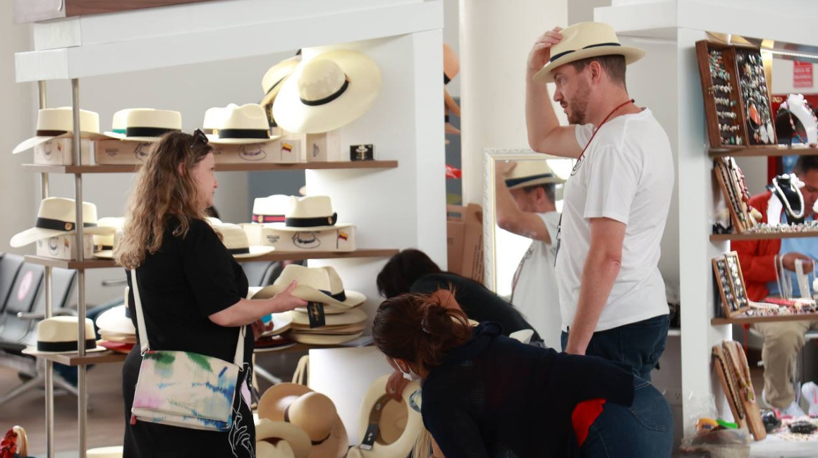 Turistas extranjeros se prueban sombreros en Ecuador, en octubre de 2022.
