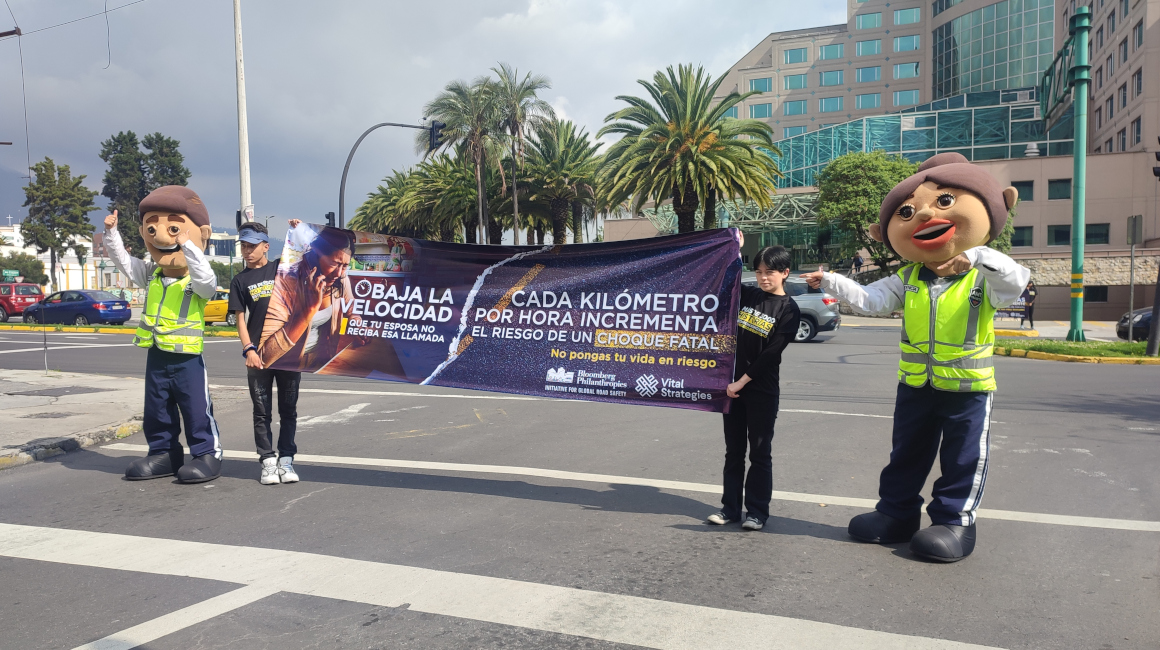 Dos personas con un cartel de la campaña 'Baja la velocidad, tu familia te espera', el 22 de noviembre de 2022 en Quito.