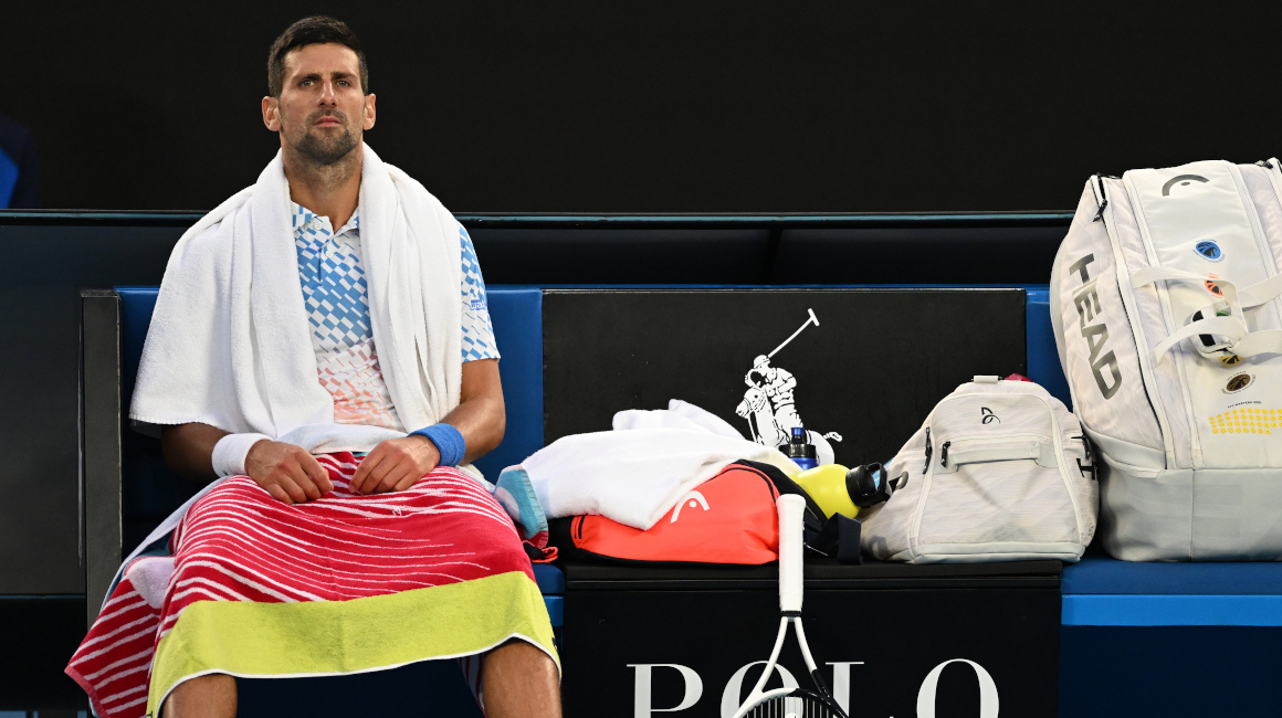 Novak Djokovic espera mientras Enzo Couacaud recibe atención médica durante su partido de segunda ronda en el Abierto de Australia, el 19 de enero de 2023.