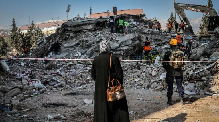 Una mujer mira los trabajos de búsqueda de cuerpos en los escombros, en la ciudad turca de Kahramanmaras.