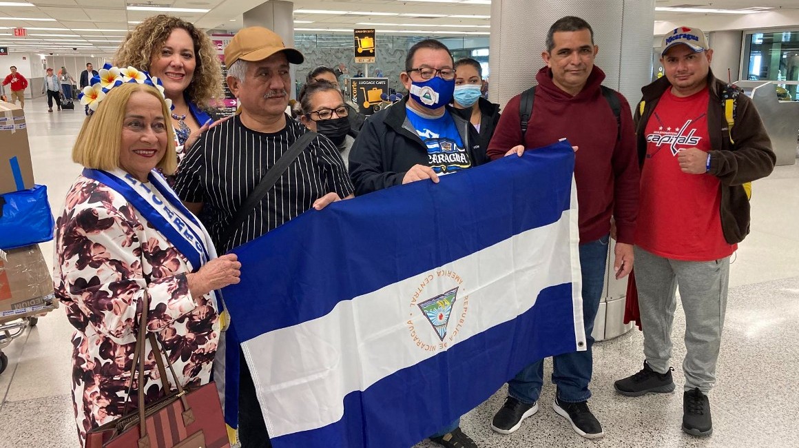 Exiliados de Nicaragua muestran la bandera de su país al llegar al aeropuerto de Miami.