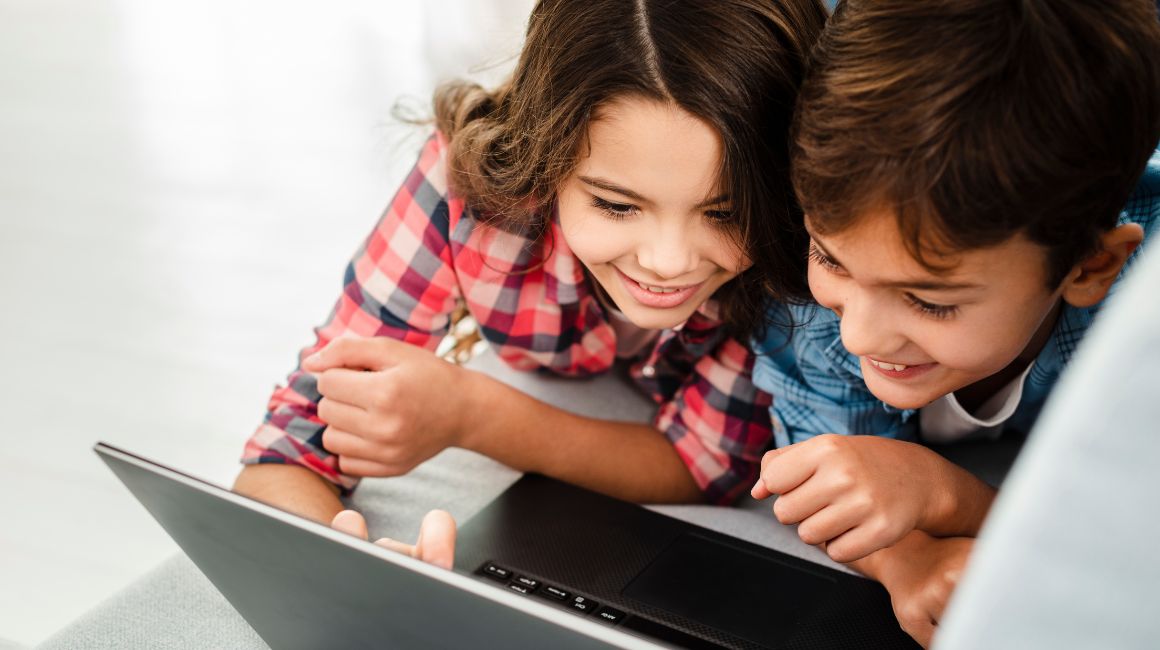 Dos niños felices usando una computadora portátil