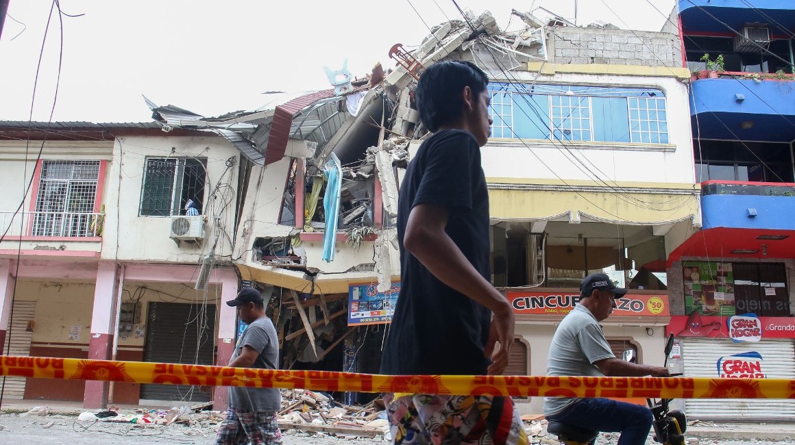 Personas pasan frente a una edificación afectada por el terremoto del 18 de marzo, en Pasaje.