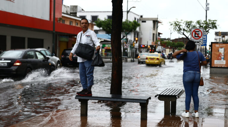 Dos personas en medio de la calle Quito, de Guayaquil, durante las inundaciones de 23 de marzo de 2023.