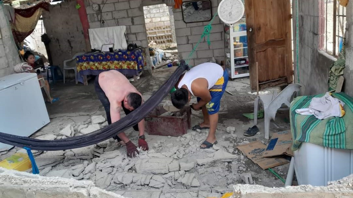 Dos hombres recogen destrozos en una pared de una casa de Puerto Salinas en el Golfo de Guayaquil.
