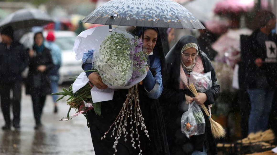 Mujeres iraníes caminan bajo la lluvia en un mercado de flores, antes del Nowruz, el Año Nuevo iraní, en Teherán, Irán, 16 de marzo de 2023.