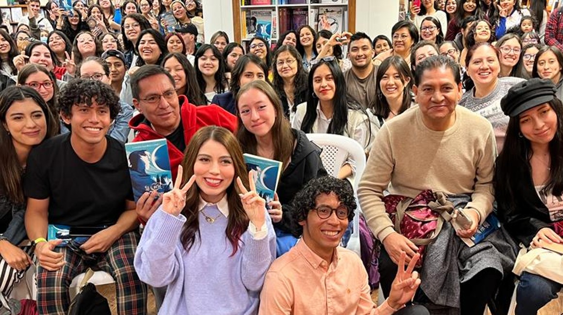 La escritora Claudia Ramírez, con el gesto de la 'V', posa con sus seguidores en la presentación de 'La corte del eclipse' en Quito.